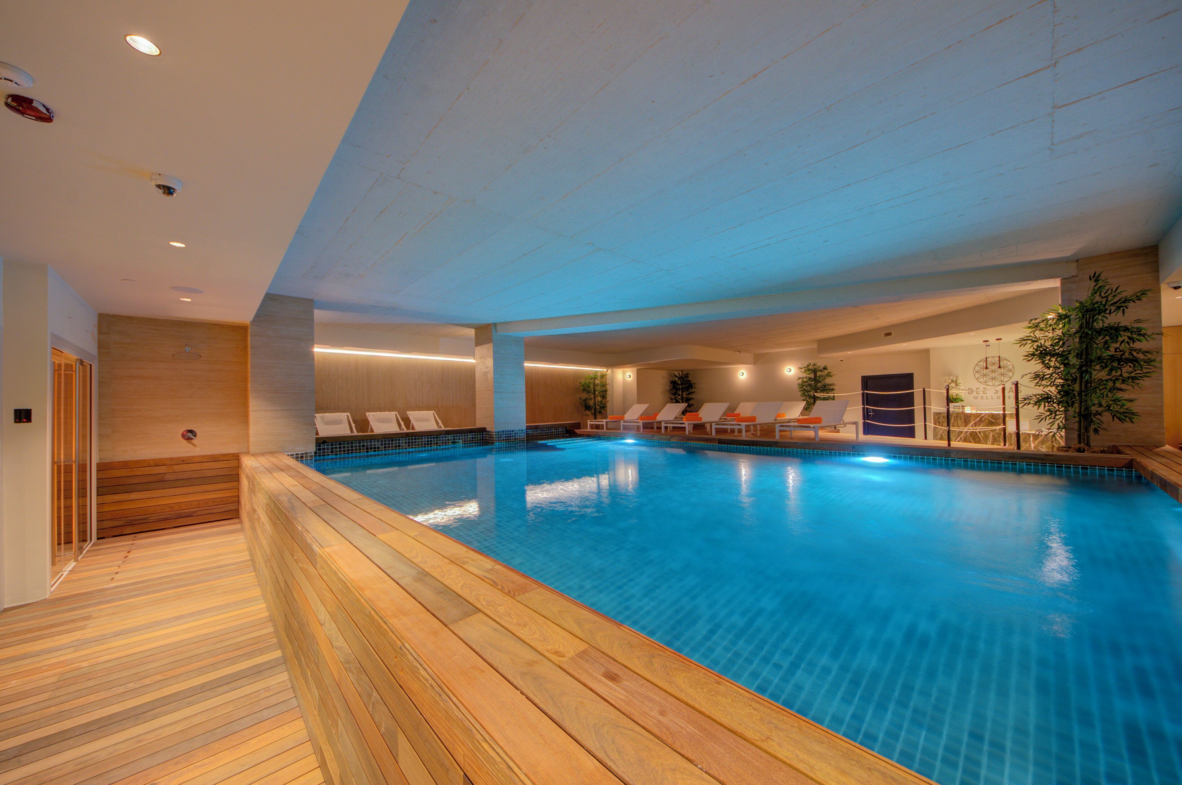 Ein Innenpool mit Holzboden, Liegestühlen und modernem Interieur.