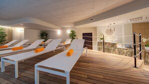 Zona de spa con tumbonas, mostrador de recepción y terraza de madera.