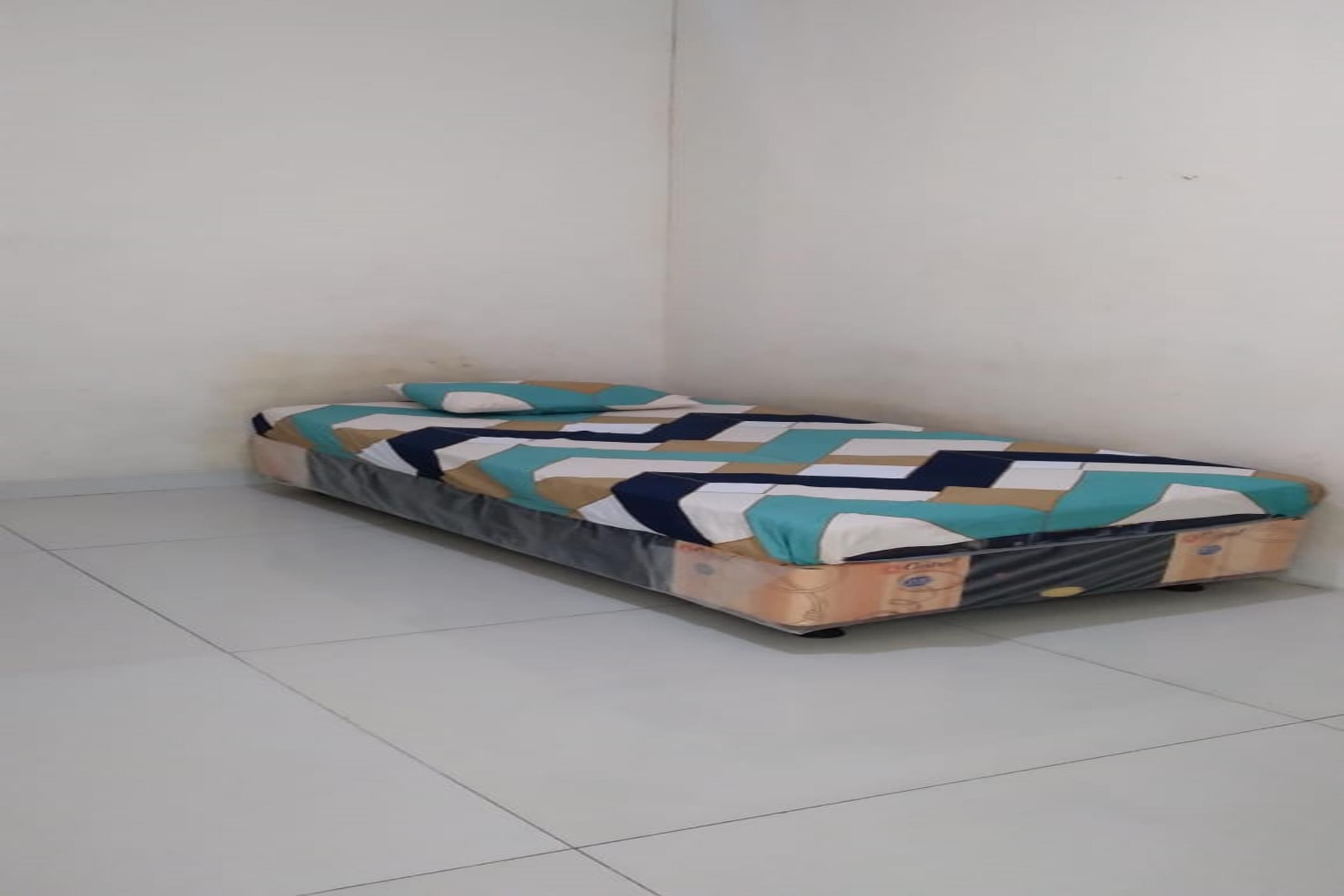 A small, single-bed room with a patterned bedspread and pillows.
