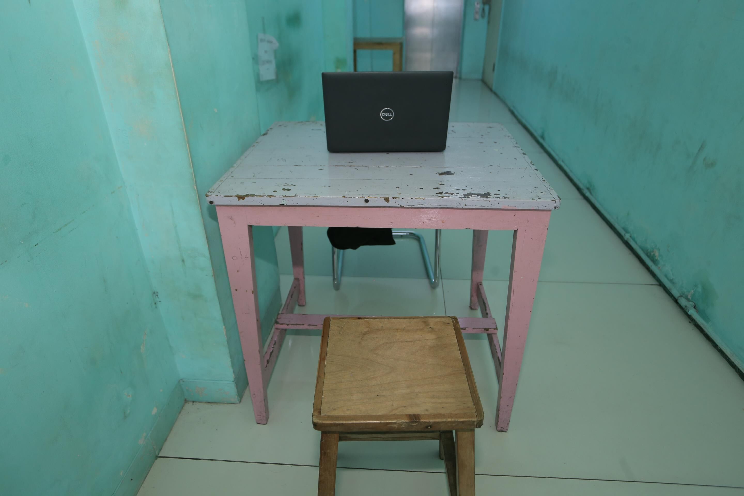 A small room with a pink table and a laptop on it.