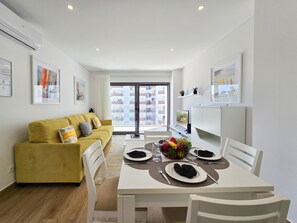 Cozy apartment with a sofa, dining area, and large window offering a view.