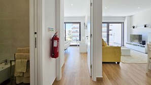 A modern apartment with a fire extinguisher mounted on the wall, a sofa, and a TV in the living area.