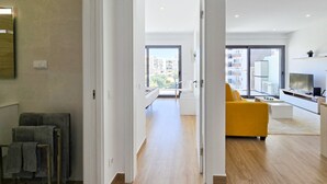A modern apartment with a bright living area, a yellow sofa, and a large window offering a city view. - Flat Praia Rocha Residence Honey Glow (Portimão)