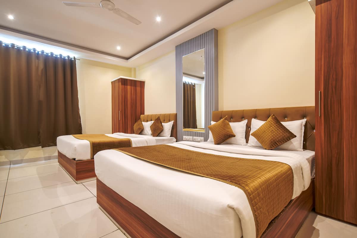 A hotel room with two beds, wooden headboards, a large mirror, and a ceiling fan.