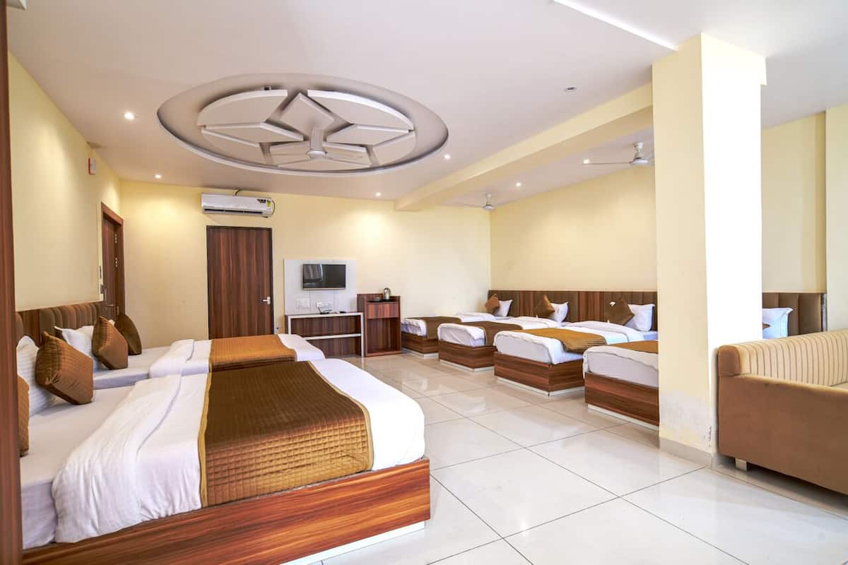 A hotel room with four beds, a TV, a desk, and a sofa.