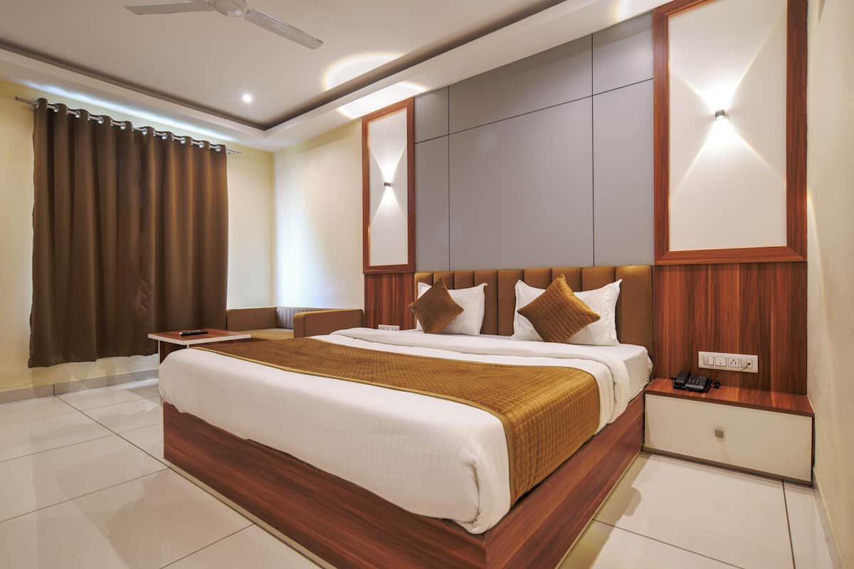 A hotel room with a large bed, a bedside table, a nightstand, and a ceiling fan.