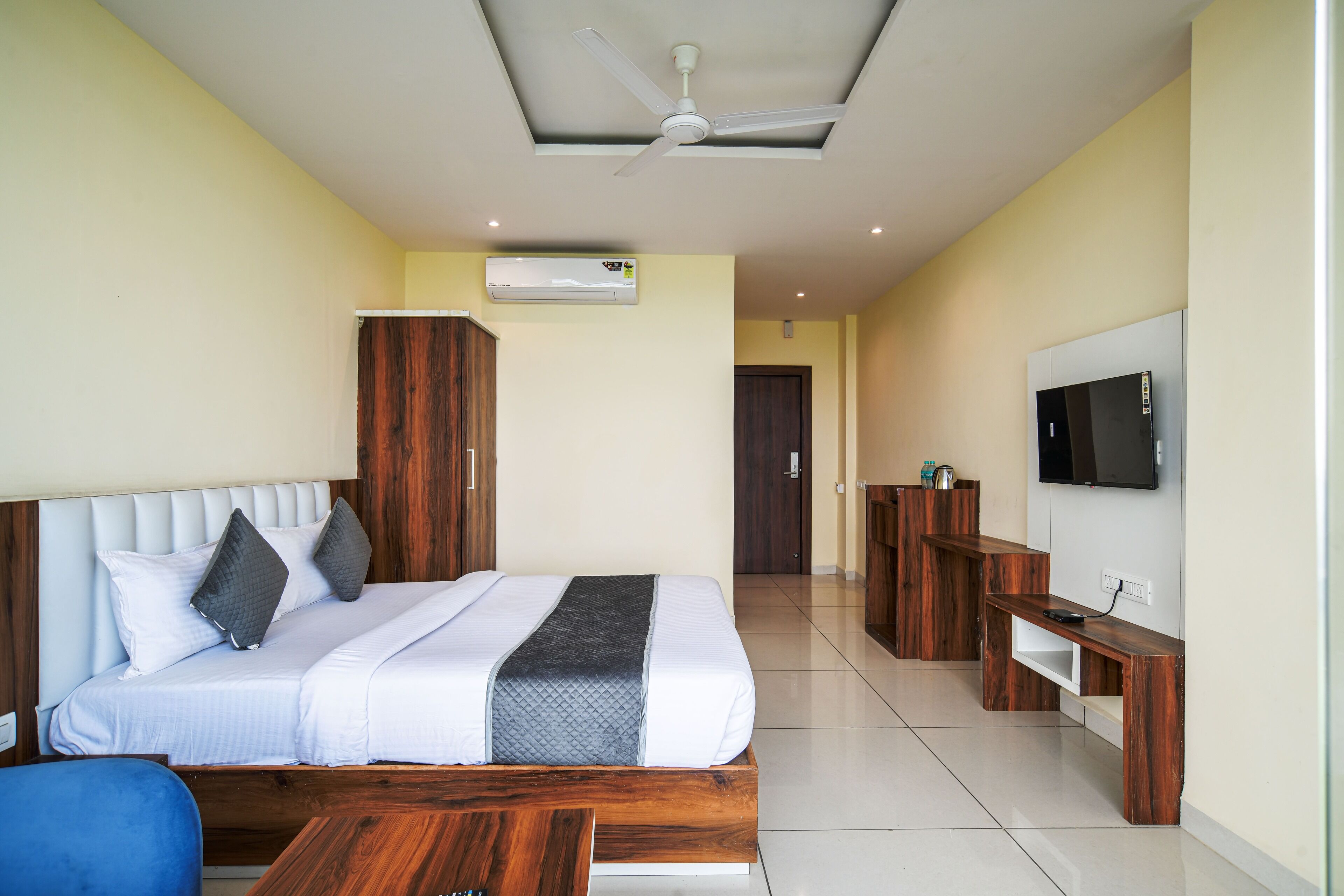 Una habitación de hotel con cama, televisor, escritorio y aire acondicionado.