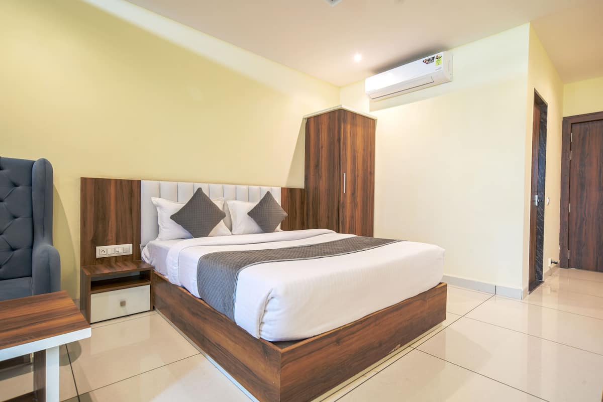 A modern bedroom with a wooden bed frame, a nightstand, a chair, and an air conditioning unit on the wall.