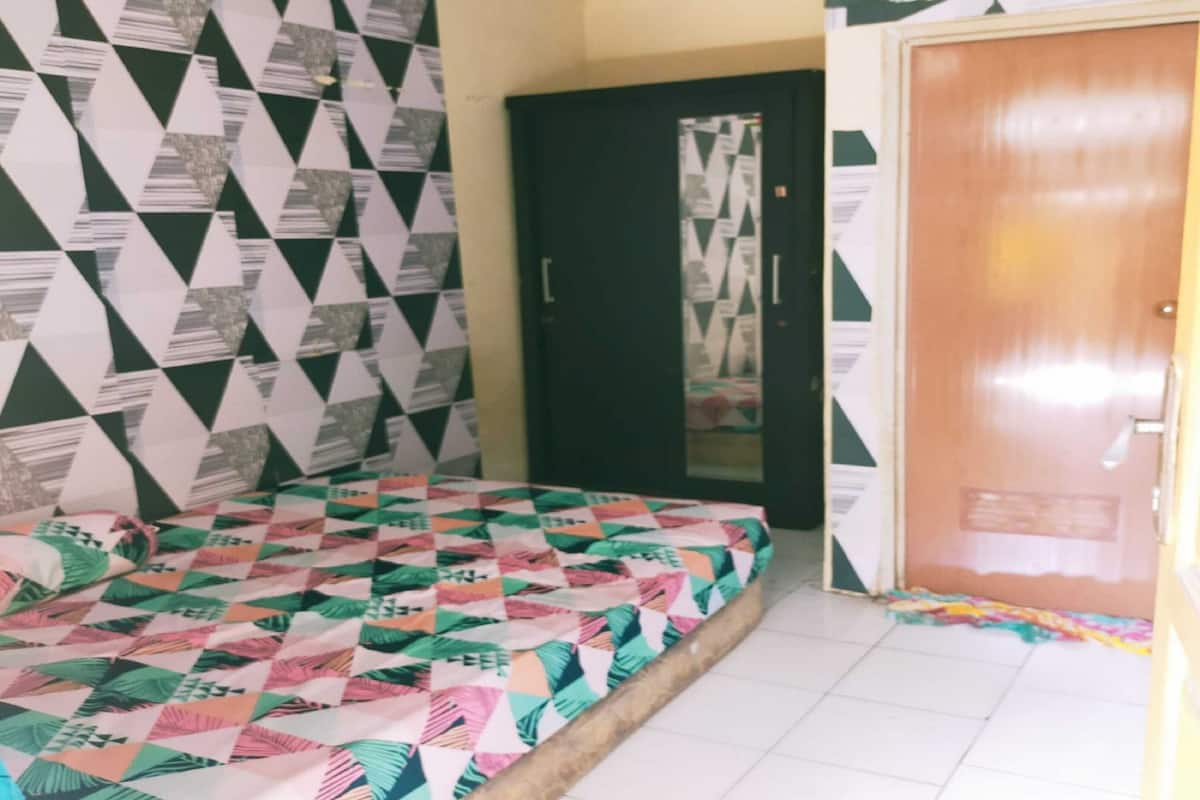 Ein Zimmer mit einem Bett, das mit einem farbenfrohen Quilting-Decken bedeckt ist, einer Tür mit einem Spiegel und strukturiertem Wandpapier.