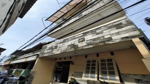 A building with a flat roof, a balcony, and a door. There are several scooters parked in front. - OYO 93887 John Residence (Jakarta)