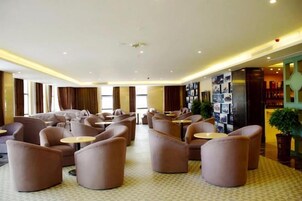 A hotel lobby with sofas, tables, and a wall with photos.