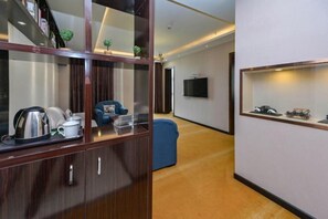 Una habitación de hotel moderna con un armario de madera, un sillón azul, un televisor y una colección de coches de juguete.