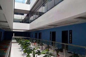 A modern hotel interior with a glass railing, potted plants, and a blue accent wall. - Chenxu Hotel (Wanyuan)