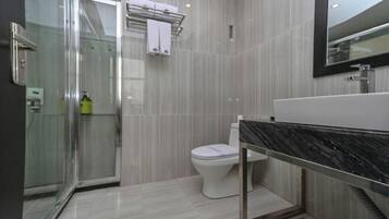 A modern bathroom with a glass shower enclosure, a white toilet, and a black marble sink.
