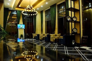 Un hall de hotel con piso reflectante, zona de estar y una pantalla de televisión.