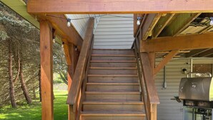 A wooden staircase leading to a deck area with a grill and outdoor seating. - Big Barn in Bemus Point, unique, peaceful, and memorable (Bemus Point)