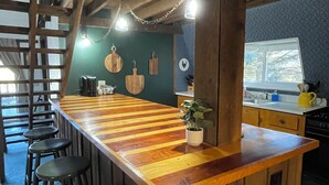 A rustic kitchen with a wooden bar, stools, and a ladder. - Big Barn in Bemus Point, unique, peaceful, and memorable (Bemus Point)