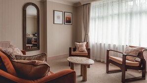 A room with striped wallpaper, a large mirror, two framed pictures, a round table, and three wooden chairs with cushions. -  The Ropemaker - A Heartwood Inn (Emsworth)