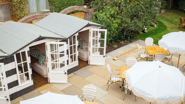 A patio area with outdoor furniture, including tables and chairs, and a small playhouse with open doors. -  The Ropemaker - A Heartwood Inn (Emsworth)