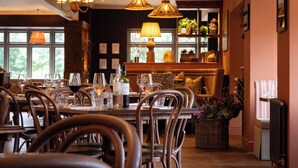 A restaurant with wooden furniture, hanging lamps, and a window with a view of trees. -  The Ropemaker - A Heartwood Inn (Emsworth)