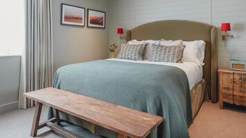 A bedroom with a bed, bedside tables, a bench, and artwork on the wall.
