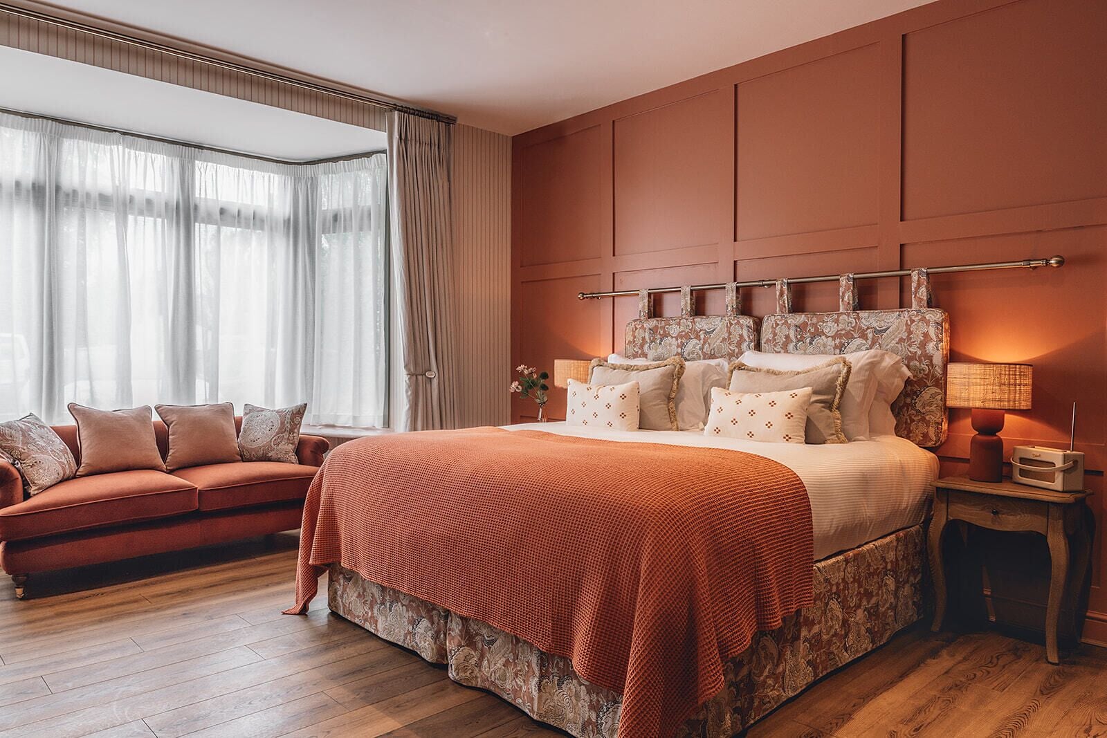 Ein Schlafzimmer mit einem großen Bett, einem Schlafsofa, einem Nachttisch und einem Fenster mit Vorhängen.