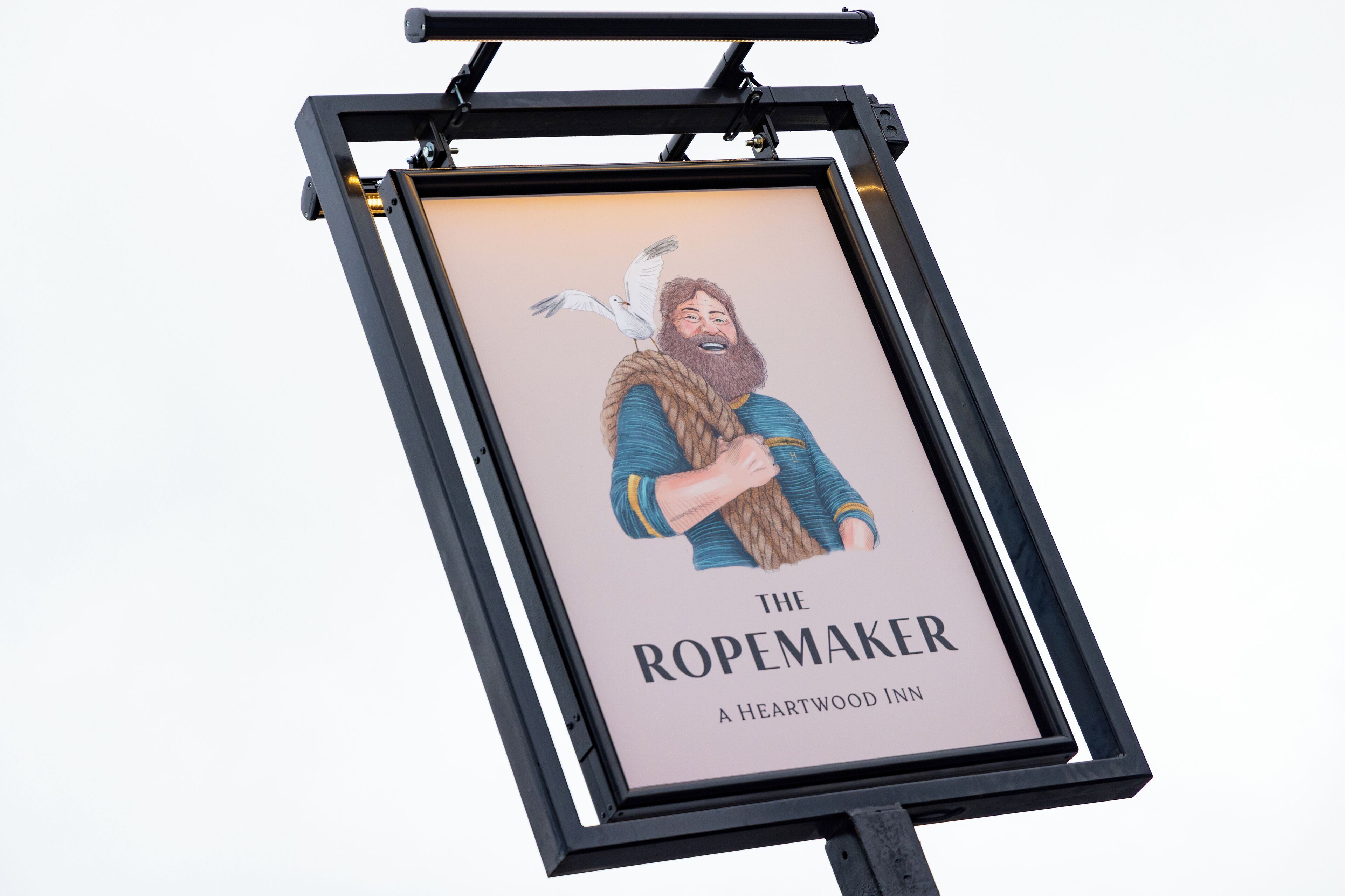 Et indrammet skilt med et menneske og en fugl, med titlen "The Ropemaker" ved Heartwood Inn.