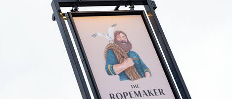 Et indrammet skilt med et menneske og en fugl, med titlen "The Ropemaker" ved Heartwood Inn.