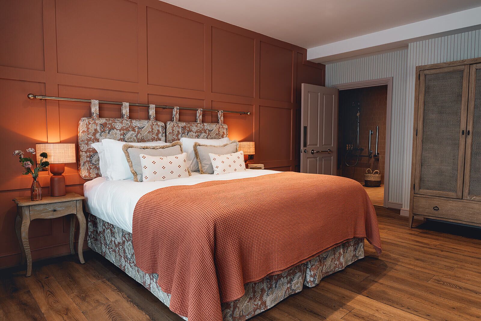 A bedroom with a large bed, wooden headboard, bedside tables, and a wardrobe.