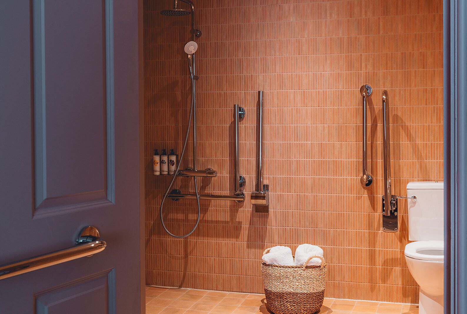 Un bagno con doccia, WC e un cesto con asciugamani.