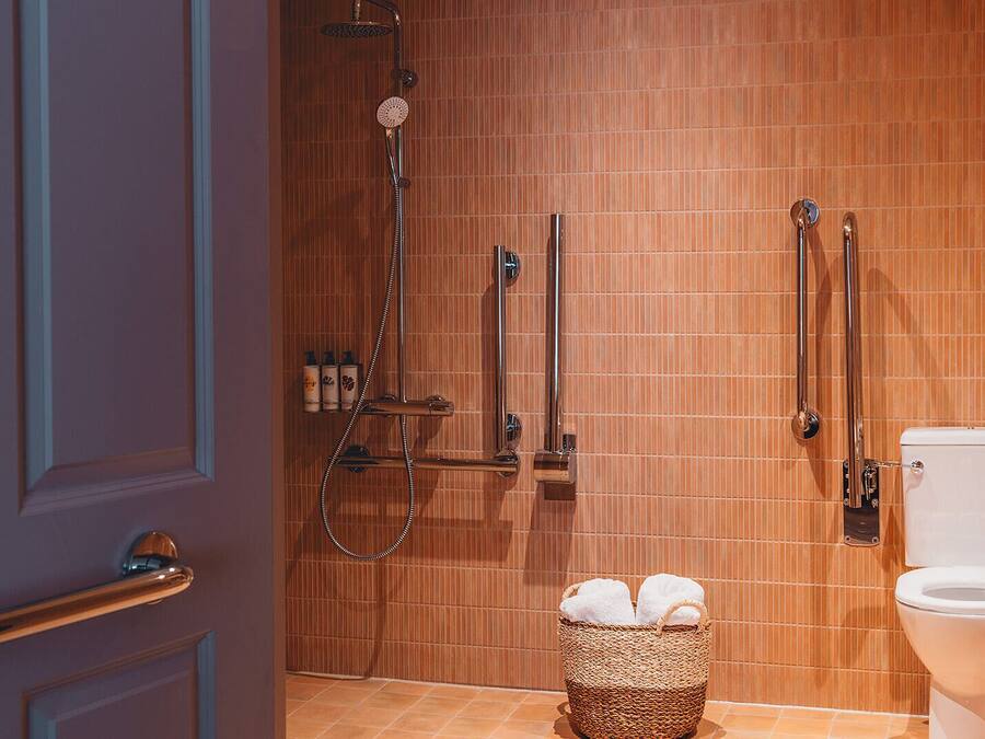 Un bagno con doccia, WC e un cesto con asciugamani.