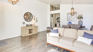 A spacious living room with a beige sofa, a wooden cabinet, and a large wall clock. - Stunning Oro Valley Home: Near Catalina State Park (Oro Valley)