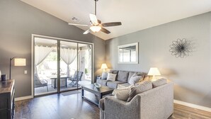 A living room with a gray sofa, a coffee table, and a ceiling fan. There is a sliding glass door leading to an outdoor patio area. - Stunning Oro Valley Home: Near Catalina State Park (Oro Valley)