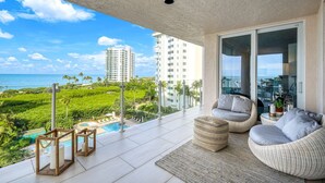 A balcony with a view of the ocean and palm trees, a pool, and outdoor seating. - Panoramic Gulf Views, Newly Renovated, Spectacular Sunsets in Naples (Naples)