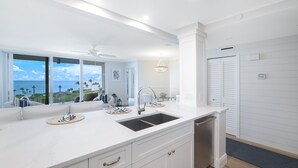 A modern kitchen with a large island, a built-in sink, and a view of the ocean. - Panoramic Gulf Views, Newly Renovated, Spectacular Sunsets in Naples (Naples)