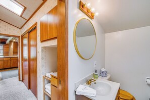 A bathroom with a wooden vanity, a sink, a mirror, and a toilet.