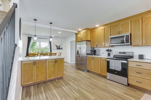 A modern kitchen with wooden cabinets, stainless steel appliances, and a large window. - Spacious Shippensburg Home, Close to Museums! (Shippensburg)
