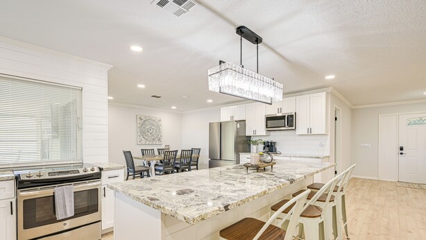 A modern kitchen with a large island, stainless steel appliances, and a chandelier. - Furnished Outdoor Area! Family Home in Spring Hill (Spring Hill)