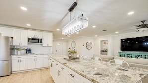 A modern kitchen with white cabinets, a granite countertop, a chandelier, and a built-in microwave. - Furnished Outdoor Area! Family Home in Spring Hill (Spring Hill)