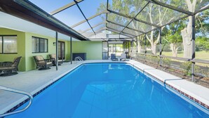 A swimming pool with a covered patio area, outdoor seating, and a view of trees. - Furnished Outdoor Area! Family Home in Spring Hill (Spring Hill)