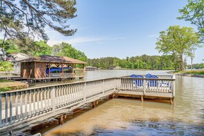 A wooden dock extending over a calm body of water, with a covered seating area and a small building. - Milledgeville Home w/ Game Room & Private Dock! (Milledgeville)