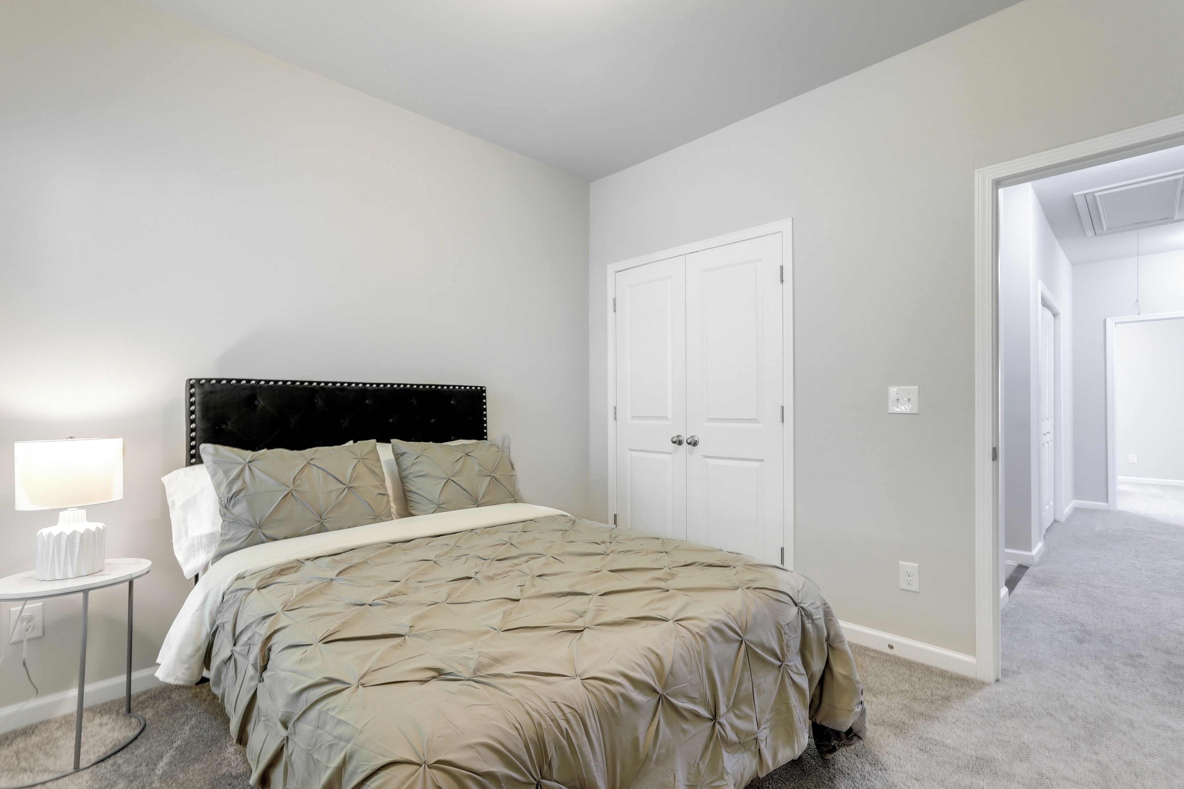 A bedroom with a bed, a nightstand, a lamp, and a closet.