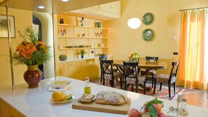 A modern kitchen with a dining area, featuring a white countertop, a wooden dining table, and chairs. - Modern Villa with Pool and Breathtaking Views on the Enchanting Amalfi Coast! (Amalfi)