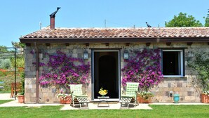 A stone house with a tiled roof, two open doors, and a small porch with two chairs and a table. - Modern Villa with Pool and Breathtaking Views on the Enchanting Amalfi Coast! (Amalfi)