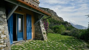 A stone house with blue shutters, a tiled patio, and a mountainous backdrop. - Charming Villa with Pool, Overlooking the Enchanting Galli Islands (Amalfi)