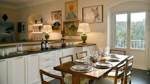 A dining area with a wooden table set for a meal, white cabinets, and artwork on the walls. - Charming Villa with Pool, Overlooking the Enchanting Galli Islands (Amalfi)