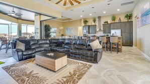 A spacious living area with a leather sectional sofa, a coffee table, and a dining area with a high table and chairs.