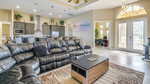 A spacious living room with a sectional sofa, a coffee table, and a kitchen area with cabinets and a microwave.