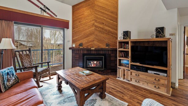 Una sala de estar acogedora con chimenea, muebles de madera y televisor.