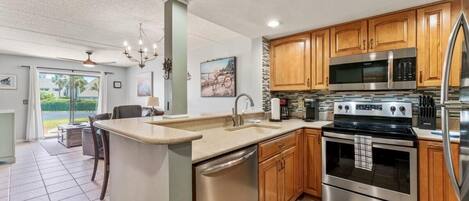 A modern kitchen with wooden cabinets, stainless steel appliances, and a large island.